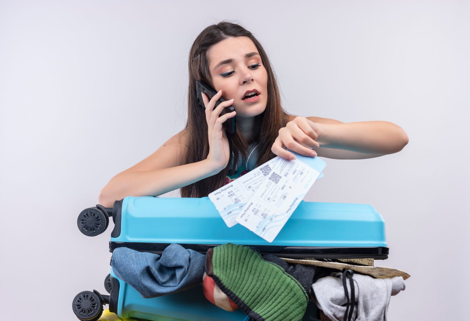 young caucasian traveler girl talking on phone holding tickets with suitcase on isolated white background